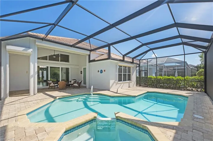 Screened outdoor living area featuring a freeform swimming pool with integrated spa