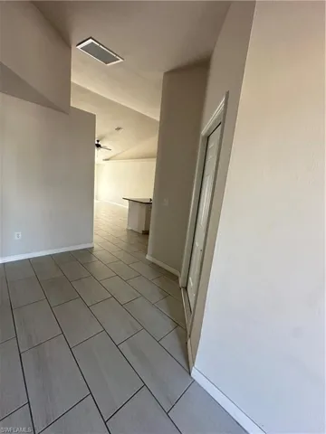 Corridor with lofted ceiling and light tile patterned floors