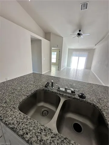 Kitchen view of light stone countertops and ceiling fan