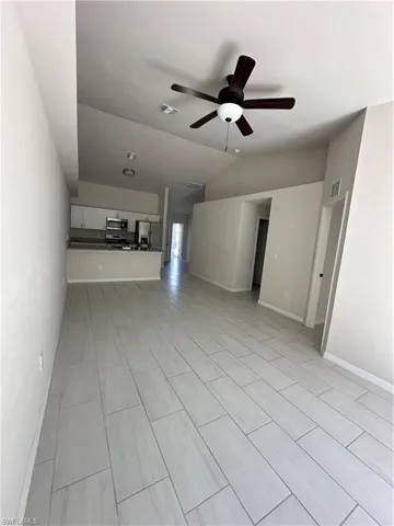 Unfurnished living room with a ceiling fan, vaulted ceiling, and wood tiled floors