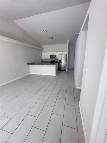 Unfurnished living room with baseboards and vaulted ceiling