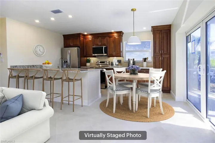 Kitchen with a breakfast bar area, pendant lighting, stainless steel appliances, light stone countertops, and backsplash