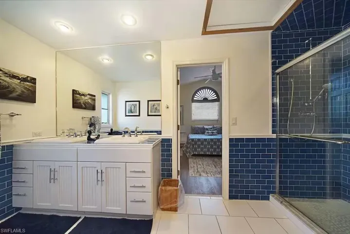 Bathroom featuring ensuite bathroom, a shower stall, double vanity, and tile patterned flooring