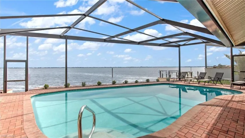 Swimming pool with a water view, a patio area, and a lanai