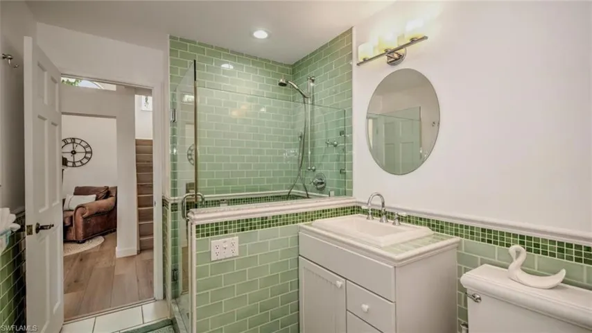 Guest Bathroom downstairs with tile walls, a tile shower, vanity, a wainscoted wall, and recessed lighting