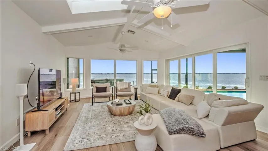 Living room with light wood finished floors, a ceiling fan, and a skylight