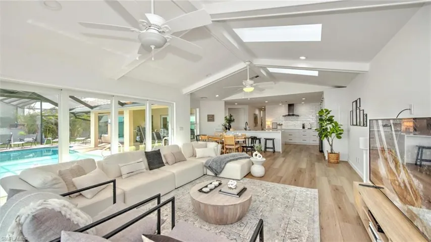 Living area with ceiling fan, light wood-style flooring, a skylight, and recessed lighting