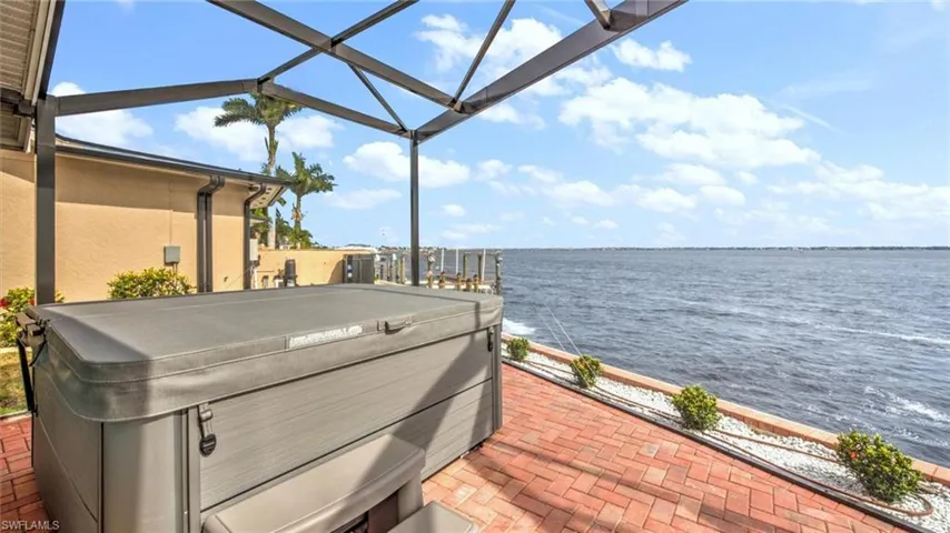 Pool area with a hot tub, a water view, a patio, and a lanai