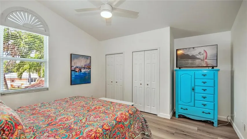 Guest Bedroom upstairs featuring light wood-style floors, multiple closets, lofted ceiling, and a ceiling fan
