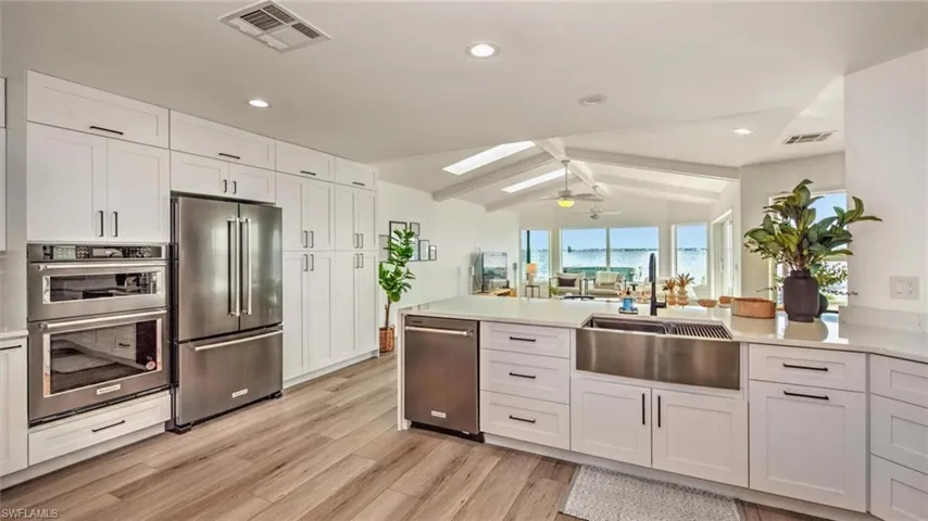 Kitchen featuring appliances with stainless steel finishes, light wood-style floors, a peninsula, light countertops, and recessed lighting