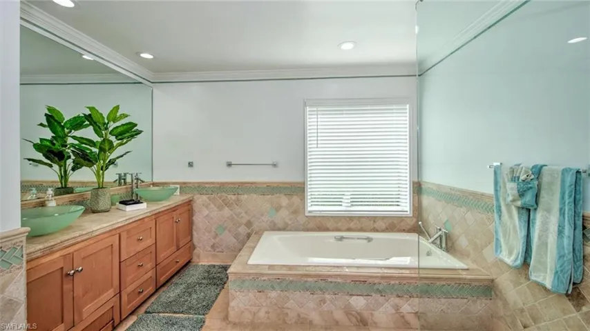 Master bath featuring double vanity, wainscoting, a garden tub, tile walls, and tile patterned floors