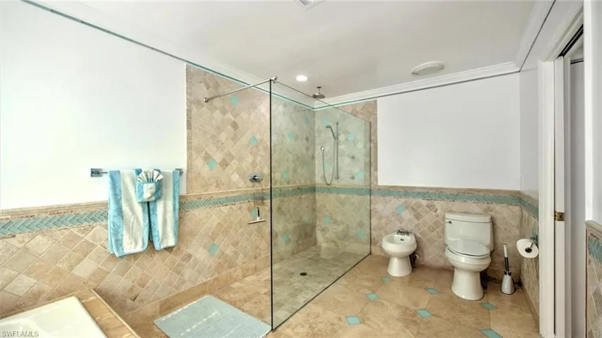 Master bath featuring tile walls, a wainscoted wall, a walk in shower, a bidet, and tile patterned floors