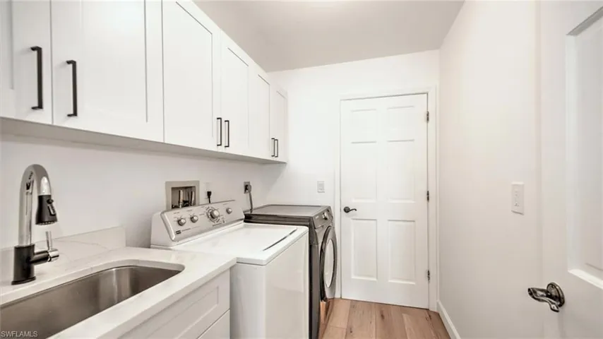 Laundry area with cabinet space, washing machine and clothes dryer, and light wood-type flooring