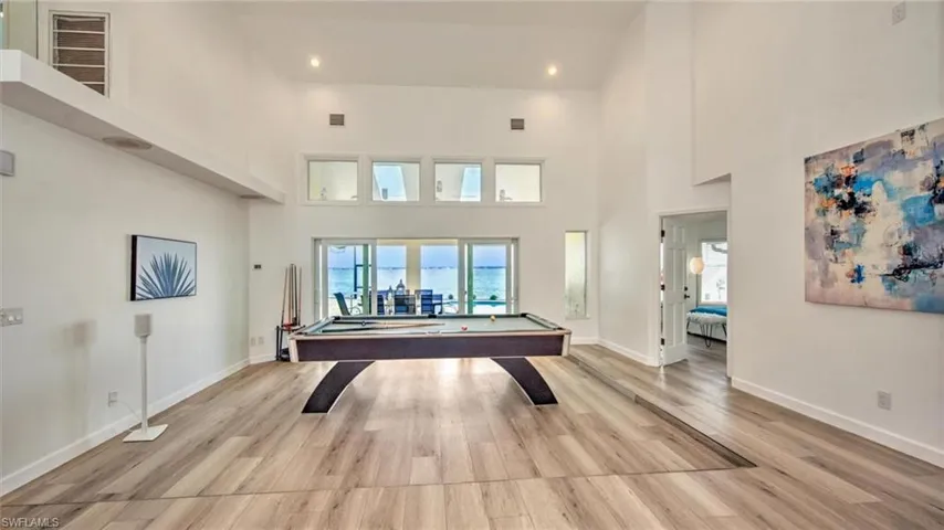 Playroom with light wood finished floors, billiards table, a high ceiling, and recessed lighting
