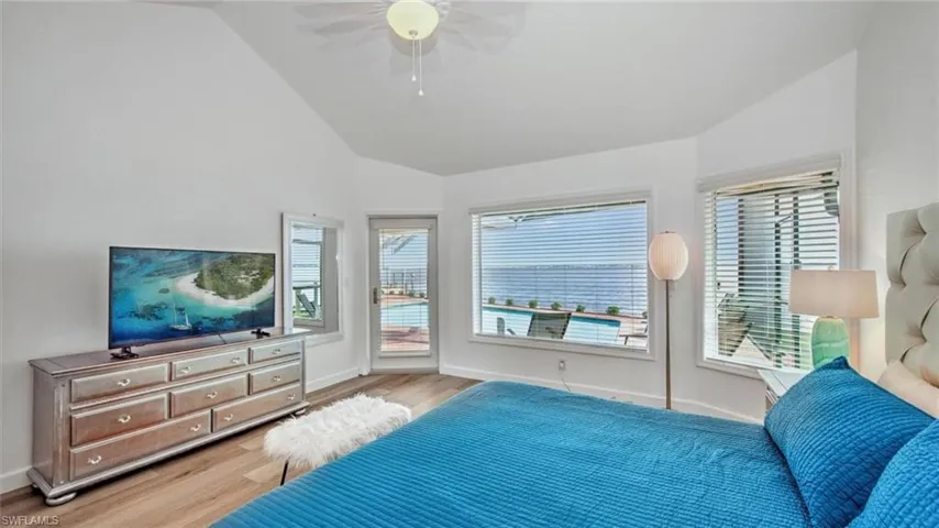 Master Bedroom with access to exterior, light wood-type flooring, multiple windows, ceiling fan, and high vaulted ceiling