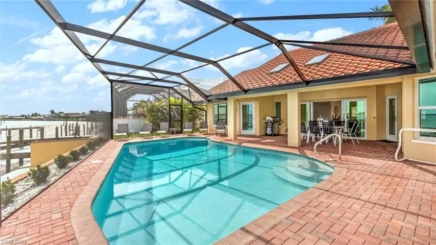 Swimming pool with grilling area, a patio area, and glass enclosure
