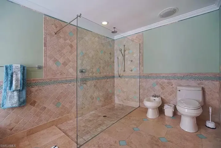 Master bathroom with tile walls, walk in shower, a bidet, crown molding, and tile patterned flooring