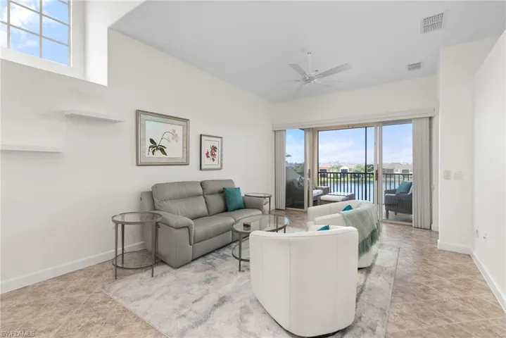 Living room with light tile patterned flooring, a water view, and ceiling fan