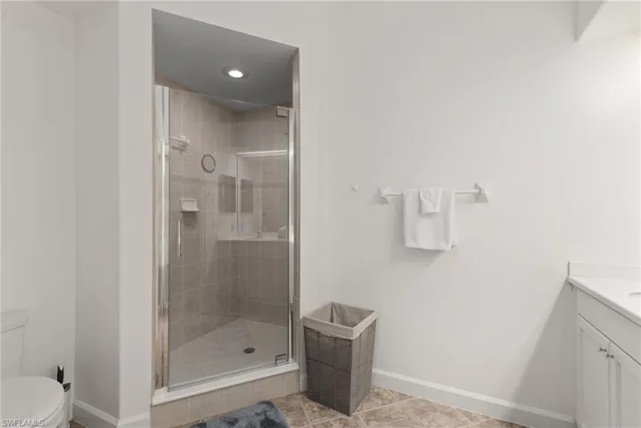 Bathroom with vanity, a shower with door, tile patterned flooring, and toilet