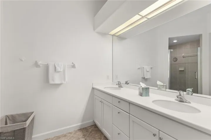Bathroom with tile patterned floors, double sink vanity, and an enclosed shower