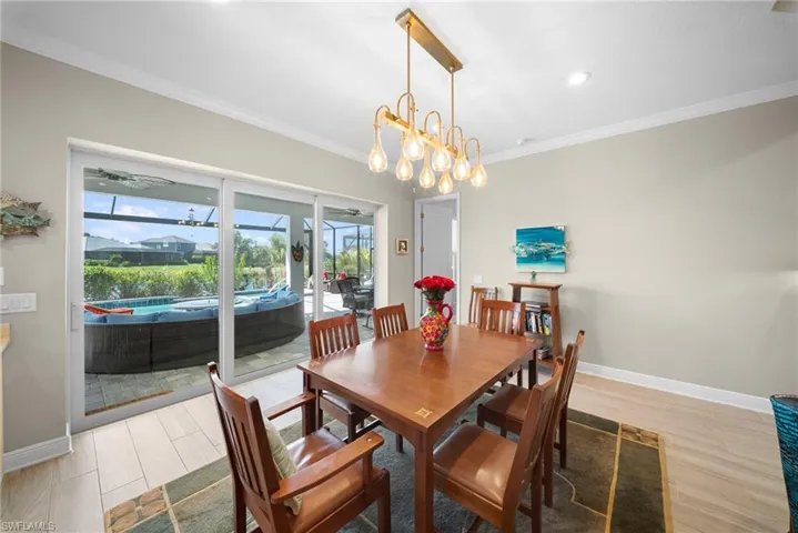 Dining area featuring light-toned flooring, a modern chandelier, and sliding glass doors that provide access to an outdoor space with a hot tub