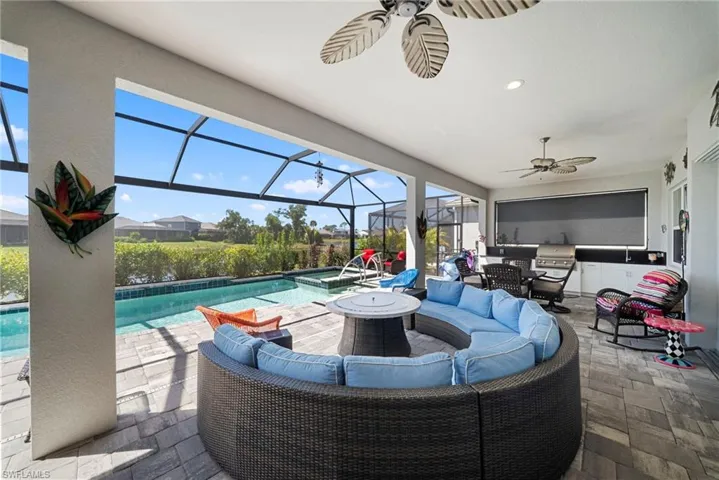 Expansive covered patio with screened enclosure, featuring a swimming pool, integrated spa, and an outdoor kitchen with a grill
