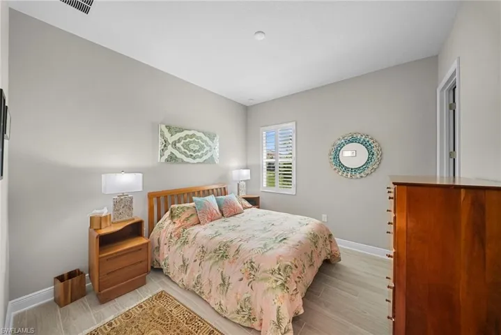The bedroom features light-colored walls and flooring, with a window providing natural light
