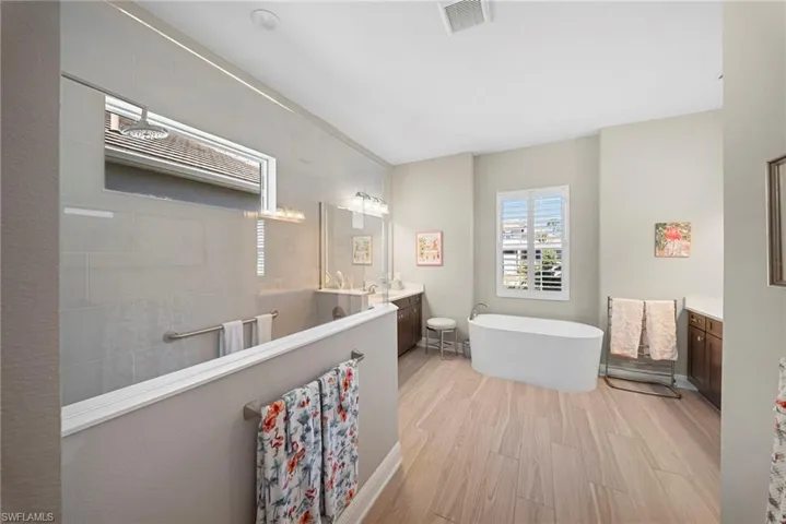 The bathroom features a standalone bathtub, a spacious walk-in shower with a glass enclosure, and light-toned flooring