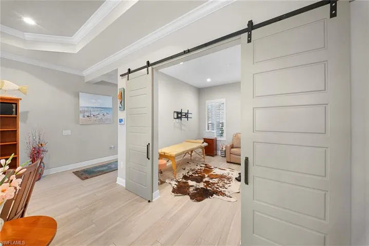 The property features barn doors with black hardware, light-colored flooring, and a window with white blinds