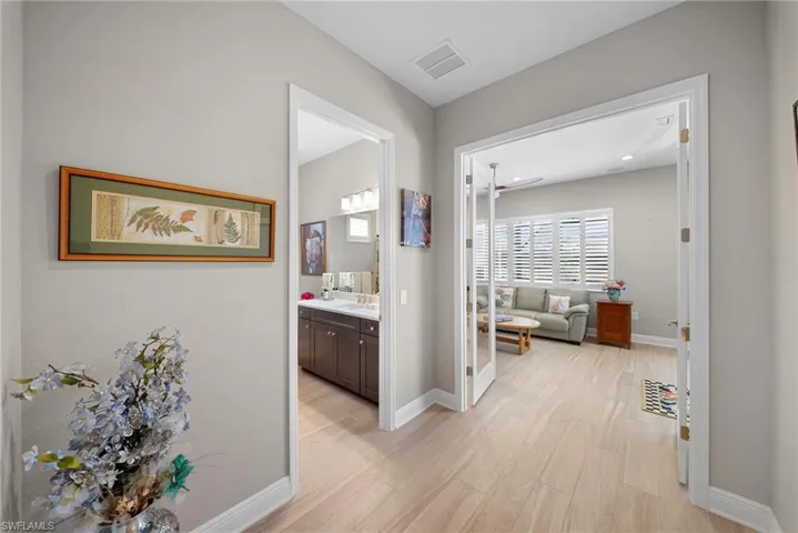 This property features light-toned flooring throughout, with a room accessible through French doors, and another room with a vanity visible