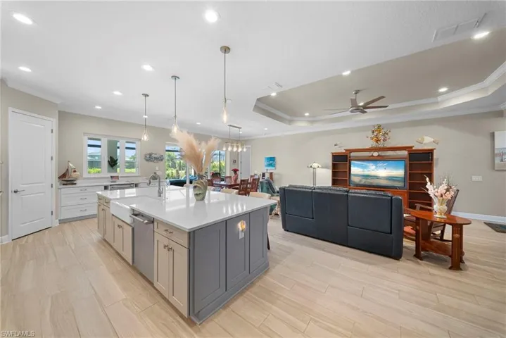 The open concept living area features light-toned flooring, recessed lighting, and a kitchen island with a farmhouse sink