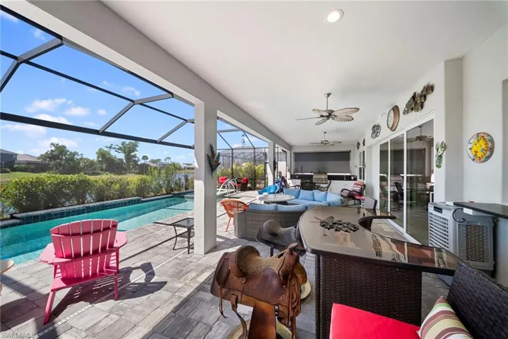 Expansive screened-in lanai with a swimming pool, pavers, and views of a body of water with lush landscaping