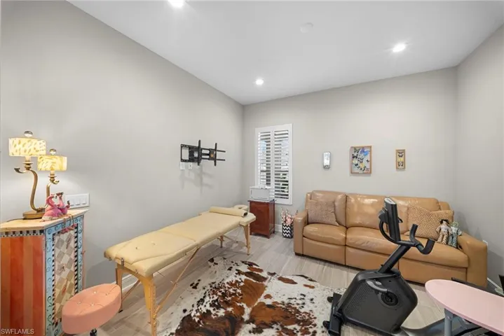 This versatile room features light-toned walls, recessed lighting, and light-colored flooring