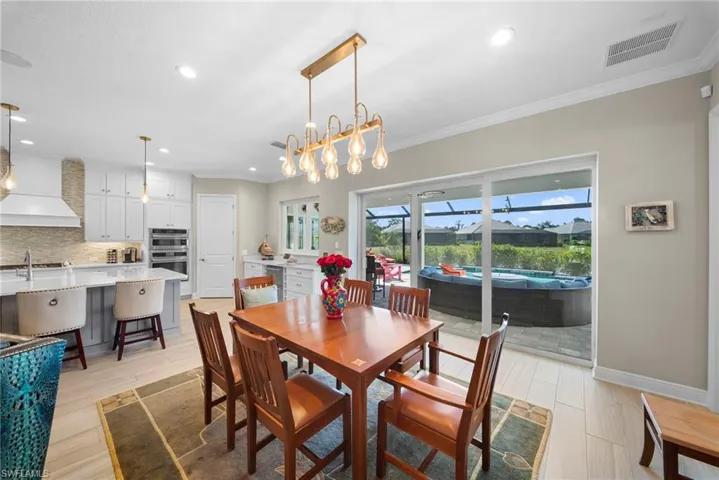 This bright interior features a modern kitchen with a large island and light-colored cabinetry, complemented by a dining area with a chandelier