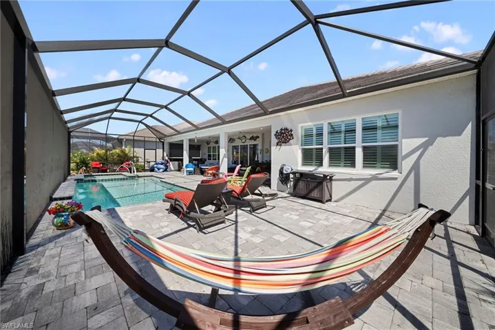 The property features a screened-in patio area with a swimming pool, paved flooring, and a covered lounge space