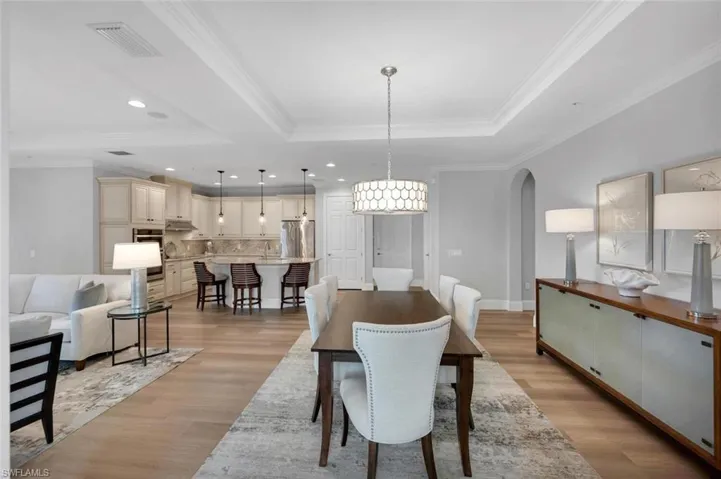 Dining space with a raised ceiling, light hardwood / wood-style flooring, and ornamental molding