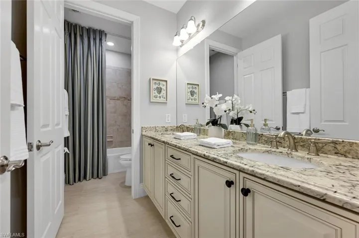 Full bathroom with vanity, tiled shower / bath combo, and toilet