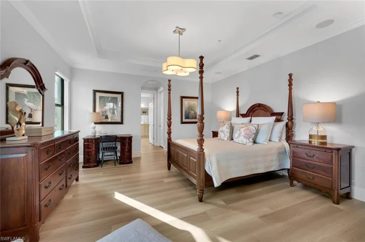 Bedroom with a raised ceiling, crown molding, and light hardwood / wood-style floors