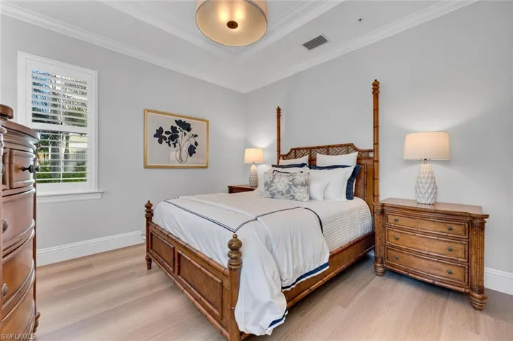 Bedroom with a raised ceiling, light hardwood / wood-style floors, and ornamental molding