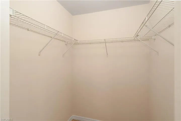 Corner closet with white wire shelving, extending along two walls