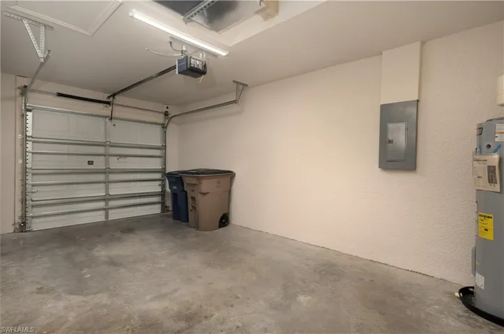 Single-car garage featuring a sectional overhead door with an automatic opener, concrete flooring, and a water heater