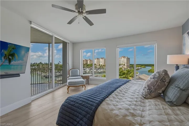 Bedroom with access to exterior, light wood-style floors, ceiling fan, and a water view