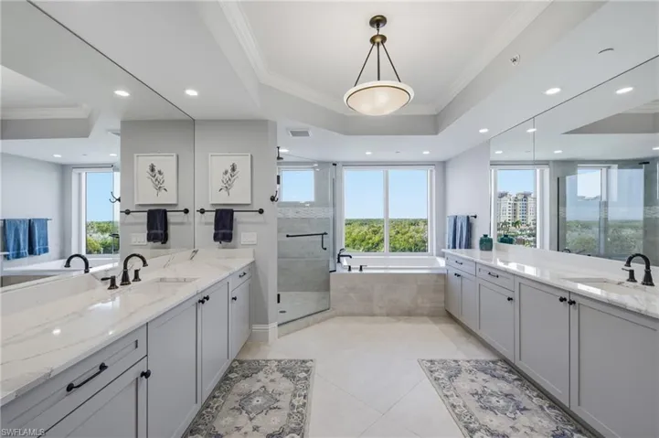 Bathroom featuring crown molding, a bath, two vanities, a stall shower, and recessed lighting