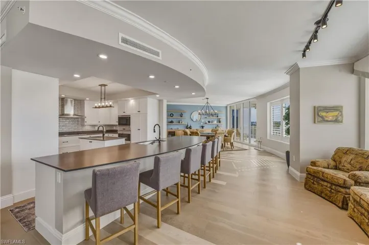 Kitchen with ornamental molding, open floor plan, white cabinets, tasteful backsplash, and a kitchen bar