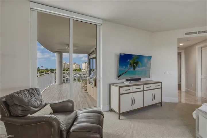 Living area with light carpet, floor to ceiling windows, and ceiling fan
