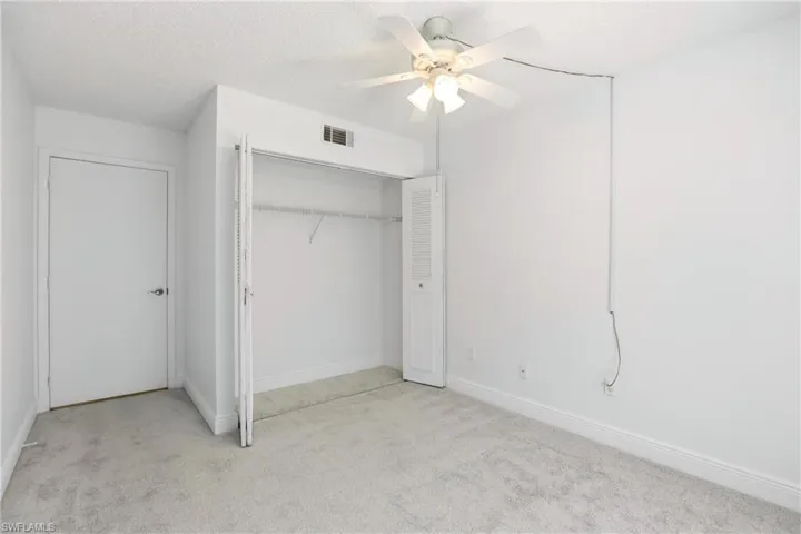 Unfurnished bedroom featuring light carpet, a closet, a textured ceiling, and a ceiling fan