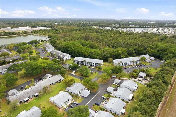 Aerial perspective of suburban area featuring a nearby body of water and a heavily wooded area