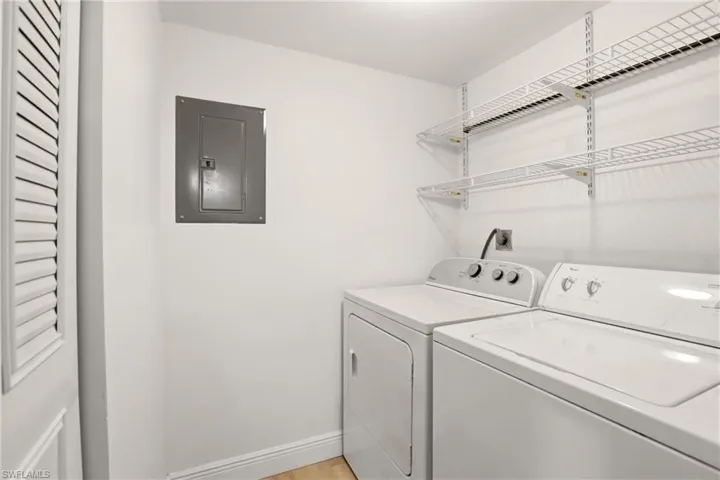 Laundry area featuring electric panel, separate washer and dryer, and light wood finished floors