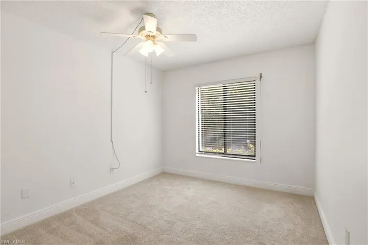 Unfurnished room featuring light colored carpet, a textured ceiling, and ceiling fan
