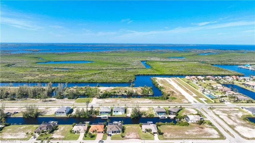 Aerial perspective showcasing a residential area with canal access, undeveloped lots, and a distinct airstrip